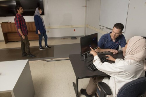 University of New Brunswick professor Erik Scheme, second from right, is shown in his lab at UNB where they use pressure-sensitive floor tiles to analyze people's gait in Fredericton, New Brunswick on Friday August 4, 2023. Here Scheme and Mayssa Rekik, Mitacs Globalink Intern from Tunisia, right, analyze the footsteps of Arijit Samal, Mitacs Globalink Intern from India, left, and Ala Salehi, graduate student.  THE CANADIAN PRESS/Stephen MacGillivray