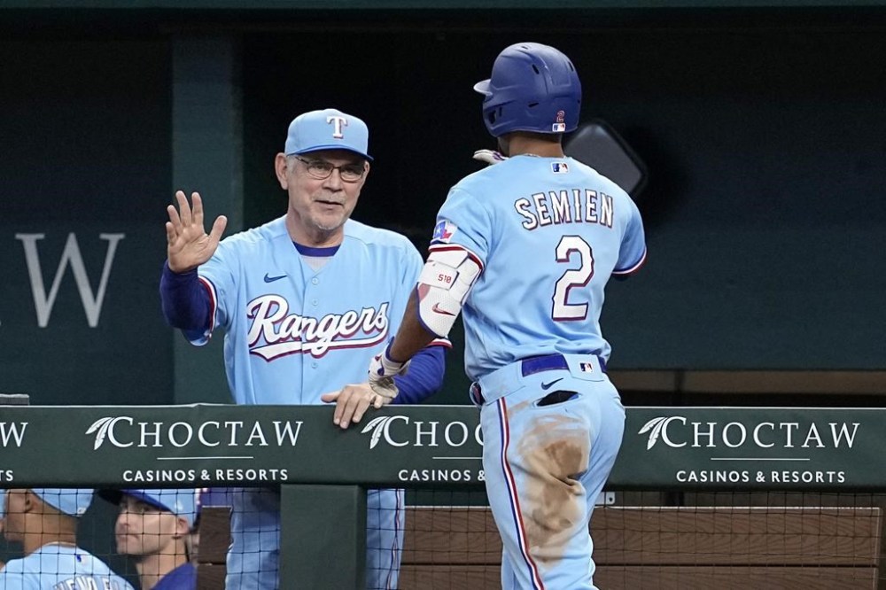 Texas Rangers manager Bruce Bochy, left, and Marcus Semien (2) celebrate after Semien's solo home run in the fifth inning of a baseball game against the Miami Marlins, Sunday, Aug. 6, 2023, in Arlington, Texas. (AP Photo/Tony Gutierrez)