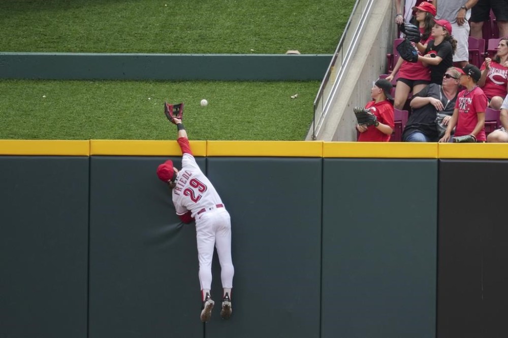 Cincinnati Reds' TJ Friedl leaps at the wall but is unable to catch a ball hit for a solo home run by Washington Nationals' Lane Thomas during the first inning of a baseball game in Cincinnati, Sunday, Aug. 6, 2022. (AP Photo/Aaron Doster)
