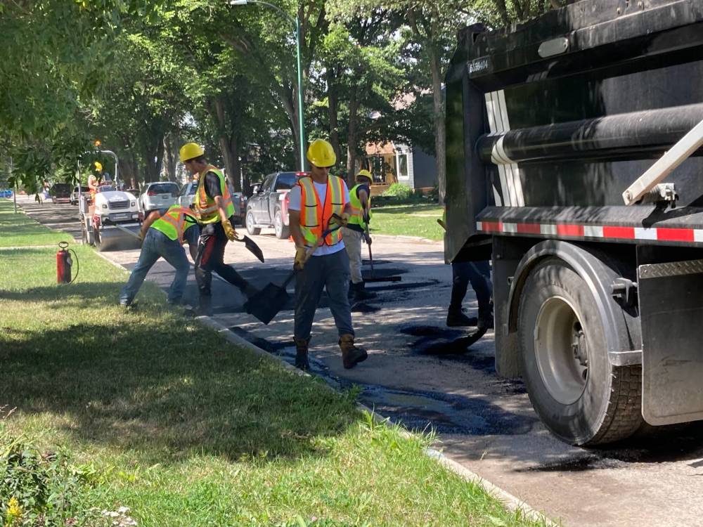 SUPPLIED
Construction workers filling in the potholes on Springside Drive containing flowers planted by Dawna Smith.