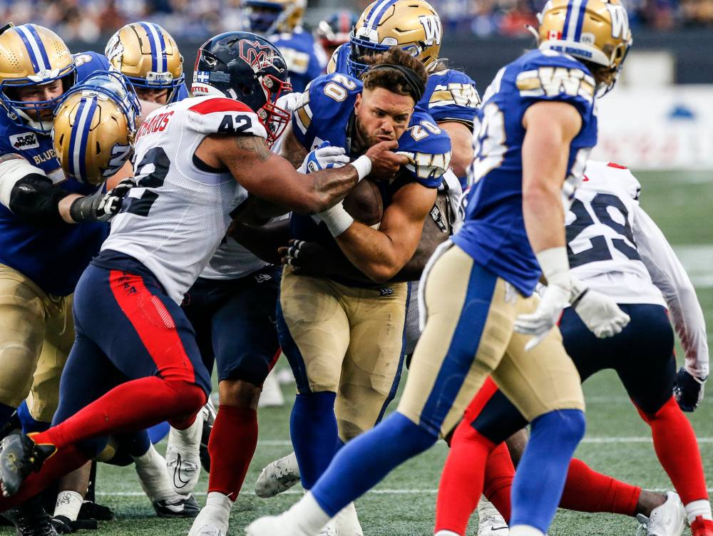 JOHN WOODS / THE CANADIAN PRESS
Bombers running back Brady Oliveira pounds out some hard yards after having his helmet torn off by the Alouettes defence Thursday night at IG Field.
