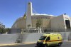 An AEK Athens team flag is at half staff outside OPAP Arena as an ambulance drives past, following overnight clashes between rival supporters in Nea Philadelphia suburb, in Athens, Greece, Tuesday, Aug. 8, 2023. European governing soccer body UEFA says it has postponed a Champions League qualifying game between AEK Athens and Croatia's Dinamo Zagreb scheduled for Tuesday because of the violence. Eight fans were injured while Greek police said Tuesday they had made 88 arrests, mostly of Croatian supporters. (AP Photo/Thanassis Stavrakis)