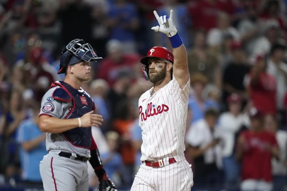 Philadelphia Phillies' Bryce Harper, right, reacts past Washington Nationals catcher Riley Adams after hitting a two-run home run during the fifth inning of the second baseball game in a doubleheader, Tuesday, Aug. 8, 2023, in Philadelphia. (AP Photo/Matt Slocum)