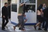 Soccer fans covering their faces, most of them from Croatia, are escorted by police as they leave the Athens Police Headquarters, Greece, Wednesday, Aug. 9, 2023. Ninety-four fans of Croatia's Dinamo Zagreb are appearing in court this morning for a preliminary hearing over Monday night's fan violence that left a fan of Greece's AEK dead and another eight people injured. (AP Photo/Petros Giannakouris)