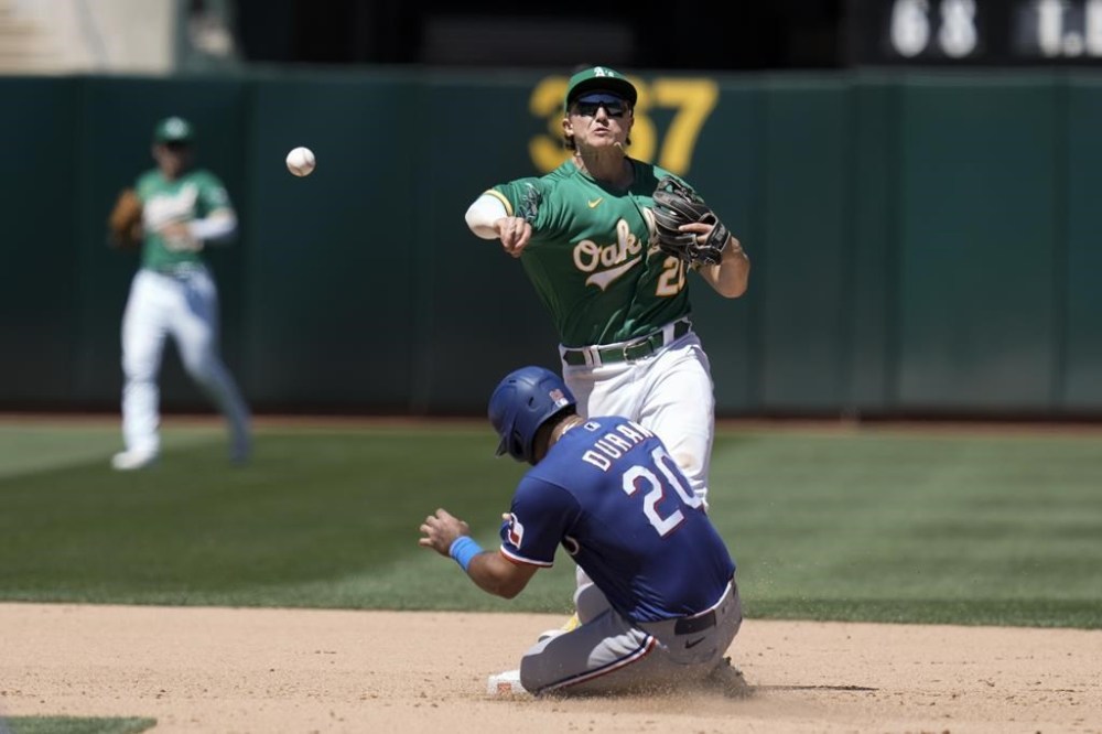 Oakland Athletics second baseman Zack Gelof, rear, throws to first base after forcing out Texas Rangers' Ezequiel Duran (20) at second during the eighth inning of a baseball game Wednesday, Aug. 9, 2023, in Oakland, Calif. Marcus Semien reached first on the play. (AP Photo/Godofredo A. Vásquez)