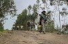 FILE — An unidentified armed militia fighter walks down a path as villagers flee with their belongings in the other direction, near the village of Chenna Teklehaymanot, in the Amhara region of northern Ethiopia Thursday, Sept. 9, 2021. Ethiopia's government and residents say the military has recaptured several areas in the embattled Amhara region from local militia fighters, while details of dozens of civilians killed have begun to emerge from the region amid an internet shutdown. The military has reclaimed control of six towns including the regional capital of Bahir Dar and the region's second-largest town, Gondar, according to a government statement on Wednesday, Aug. 9, 2023. It said curfew has been imposed in those areas and flights there are set to resume. (AP Photo, File)