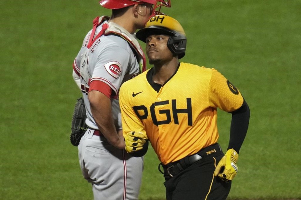 Pittsburgh Pirates' Ke'Bryan Hayes, right, crosses home plate after hitting a solo home run off Cincinnati Reds starting pitcher Andrew Abbott during the sixth inning of a baseball game in Pittsburgh, Friday, Aug. 11, 2023. (AP Photo/Gene J. Puskar)