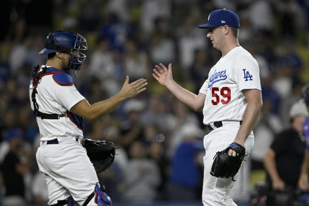 Los Angeles Dodgers relief pitcher Evan Phillips, right, celebrates with catcher Austin Barnes after striking out three Colorado Rockies batters during the ninth inning of a baseball game in Los Angeles, Saturday, Aug. 12, 2023. (AP Photo/Alex Gallardo)