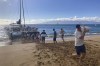A group of volunteers who sailed from Maalaea Bay, Maui, form an assembly line on Kaanapali Beach on Saturday Aug. 12, 2023, to unload donations from a boat. Maui residents have come together to donate water, food and other essential supplies to people on the western side of the island after a deadly fire destroyed hundreds of homes and left scores of people homeless. (AP Photo/Rick Bowmer)