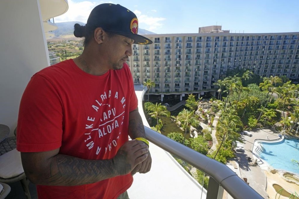 J.P. Mayoga, a chef at the Westin Maui, Kaanapali, stands on a balcony at the hotel and resort, Sunday, Aug. 13, 2023, near Lahaina, Hawaii. About 200 employees are living there with their families. Hawaii officials urge tourists to avoid traveling to Maui as many hotels prepare to house evacuees and first responders on the island where a wildfire demolished a historic town and killed dozens. (AP Photo/Rick Bowmer)