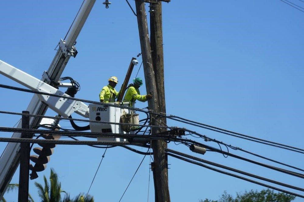 Linemen work on poles, Sunday, Aug. 13, 2023, in Lahaina, Hawaii, following a deadly wildfire that caused heavy damage days earlier. (AP Photo/Rick Bowmer)