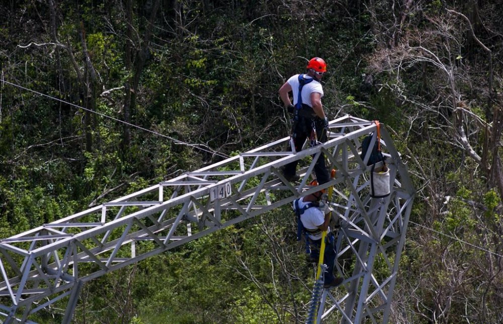 FILE - Workers restore power lines damaged by Hurricane Maria in Barceloneta, Puerto Rico, Oct. 15, 2017. Activists and environmental groups including the Sierra Club are suing on Monday, Aug. 14, 2023, Puerto Rico’s government over the planned location of dozens of renewable energy projects meant to ease the U.S. territory’s power woes. (AP Photo/Ramon Espinosa, File)
