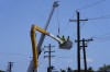 FILE - Linemen work on poles, Sunday, Aug. 13, 2023, in Lahaina, Hawaii, following a deadly wildfire that caused heavy damage days earlier. Hawaiian Electric Co. faces criticism for not shutting off the power amid high wind warnings and keeping it on even as dozens of poles began to topple. (AP Photo/Rick Bowmer, File)