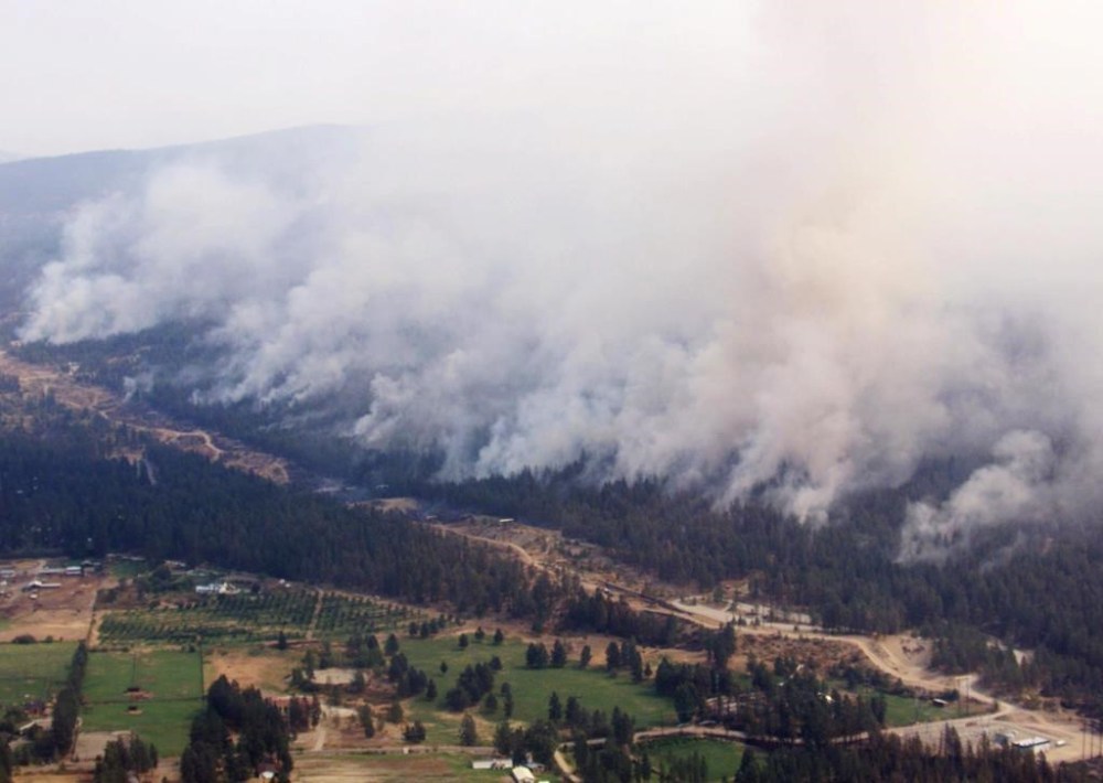 Smoke pours out from the trees as the Okanagan Mountain Park forest fire burned above the City of Kelowna, B.C., Sunday, Aug. 24, 2003. As B.C. is in the grips of a record-breaking 2023 wildfire season, the 20 year anniversary of Kelowna's firestorm year drums up mixed emotions for those who lived through it, and offers lessons in the present, they say. THE CANADIAN PRESS/Chuck Stoody
