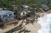 FILE - This photo provided by the Hawaii Department of Land and Natural Resources, shows a home, right, after it collapsed onto a beach on Feb. 28, 2022, in Haleiwa, Hawaii. Hawaii increasingly seems under siege from disasters, and what is increasing most is wildfire, according to an analysis of Federal Emergency Management Agency records by The Associated Press. There were as many federally-declared disaster wildfires this month in Hawaii, as in the 50 years between 1953 and 2003. (Dan Dennison/Hawaii Department of Land and Natural Resources via AP, File)