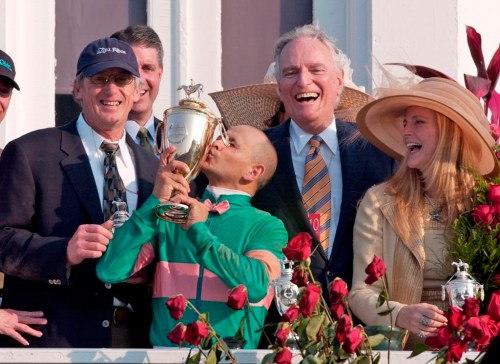 FILE - Jockey Mike Smith kisses the trophy as trainer John Shirreffs, left, and owners Jerry and Ann Moss look on after Smith rode Giacomo to win the Kentucky Derby horse race at Churchill Downs, May 7, 2005, in Louisville, Ky. While Herb Alpert and Moss were building A&M Records into a powerhouse label, Moss bought his first thoroughbred in 1970. It was the start of a love affair with horse racing that lasted the rest of his life. His family said Moss died Wednesday, Aug. 16, 2023, at age 88. (AP Photo/Ed Reinke, File)