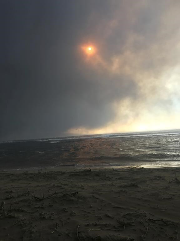 In this photo provided by Anne Landon, smoke fills the sky and blots out the sun as a deadly fire overtakes the town of Lahaina, on the Hawaiian island of Maui, Tuesday, Aug. 8, 2023. The lahaina resident was able to escape her senior apartment complex with her life. But many people, families, homes and an entire town were lost in the inferno. (Anne Landon via AP)