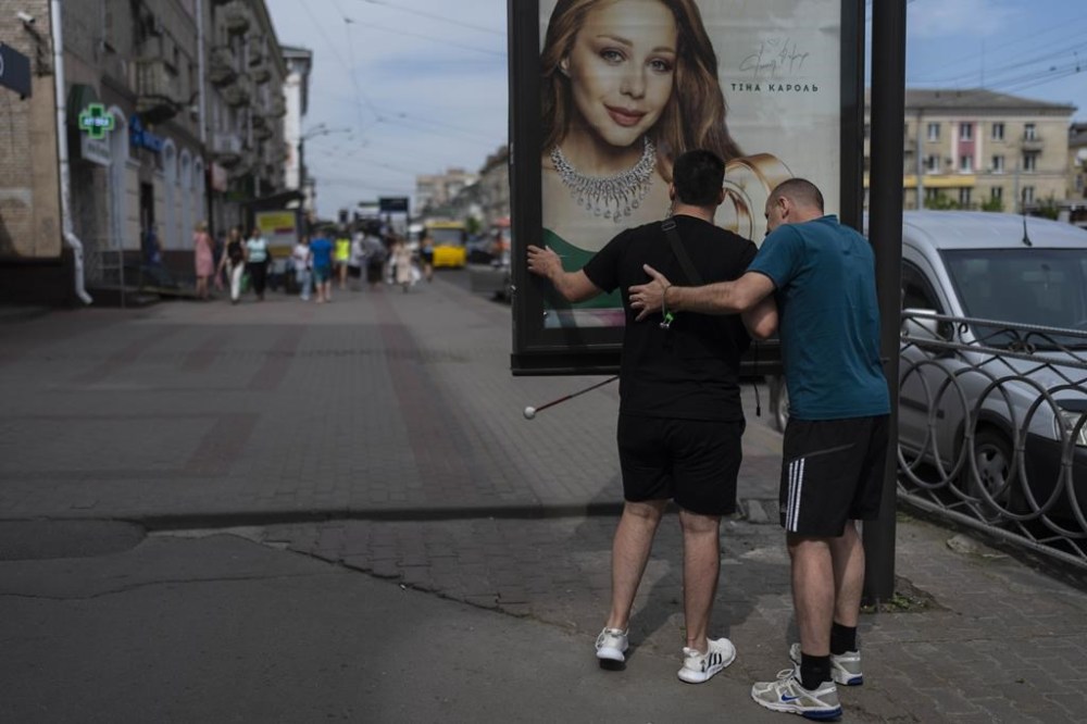 Trainer Vasyl Hoshovskyi, right, helps Denys Abdulin, a former Ukrainian soldier blinded in the war, avoid obstacles in Rivne, Ukraine, Thursday, July 20, 2023, as part of his training at a rehabilitation center designed for soldiers who lost their vision on the battlefield. (AP Photo/Jae C. Hong)