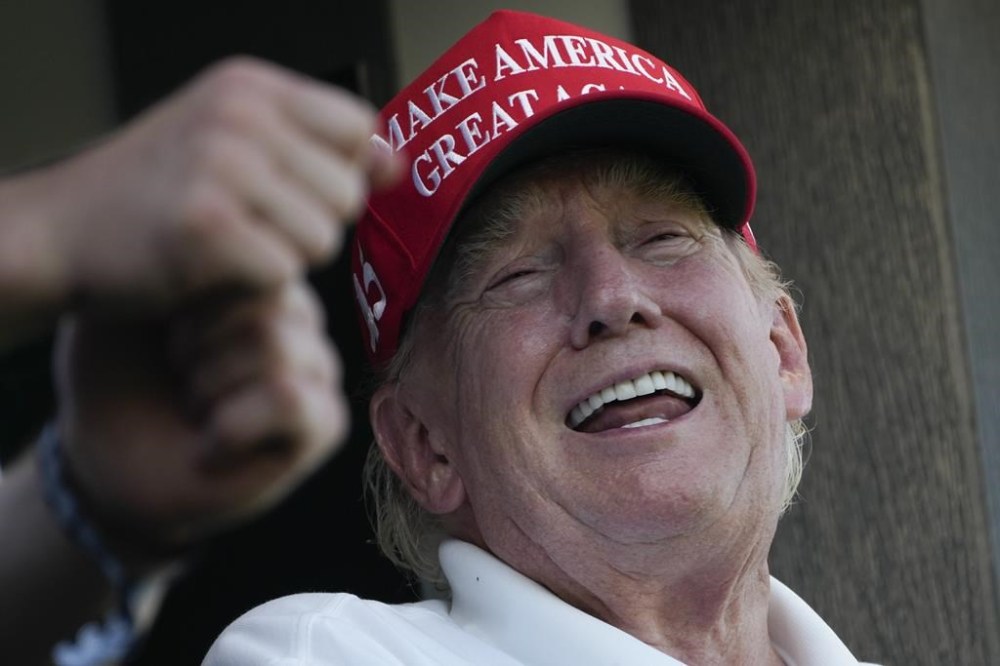 Former President Donald Trump laughs while looking over the 18th hole during the final round of the Bedminster Invitational LIV Golf tournament in Bedminster, N.J., Sunday, Aug. 13, 2023. (AP Photo/Seth Wenig)