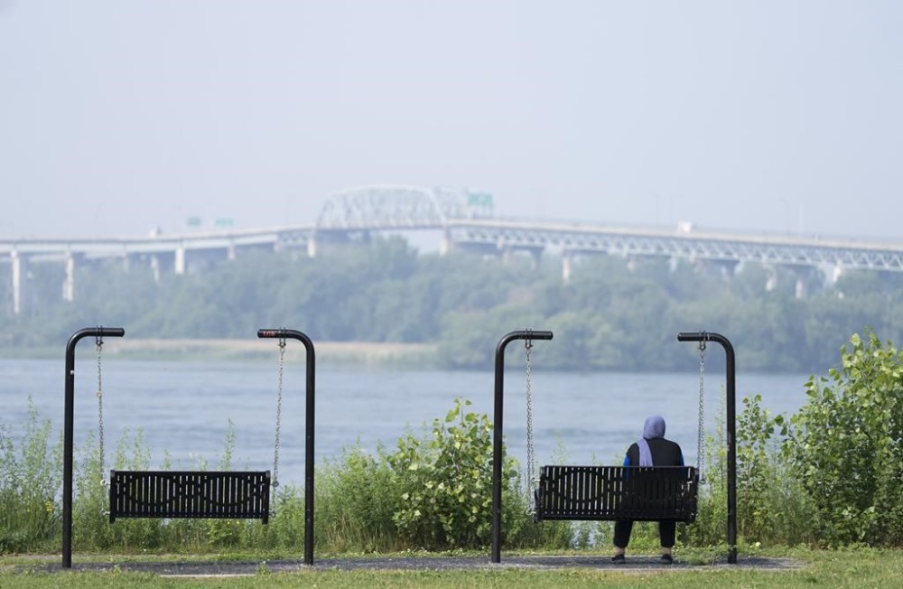 Smoke from fires in western and northern parts of Canada has created a hazardous air quality in Ontario's north. A woman looks out at the St. Lawrence River in LaSalle, Que., Friday, June 30, 2023. THE CANADIAN PRESS/Christinne Muschi