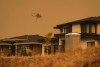 A helicopter equipped to respond to wildfires flies past homes in the Wilden neighbourhood near Knox Mountain after RCMP officers enforced a new evacuation order, in Kelowna, B.C., Friday, Aug. 18, 2023. THE CANADIAN PRESS/Darryl Dyck
