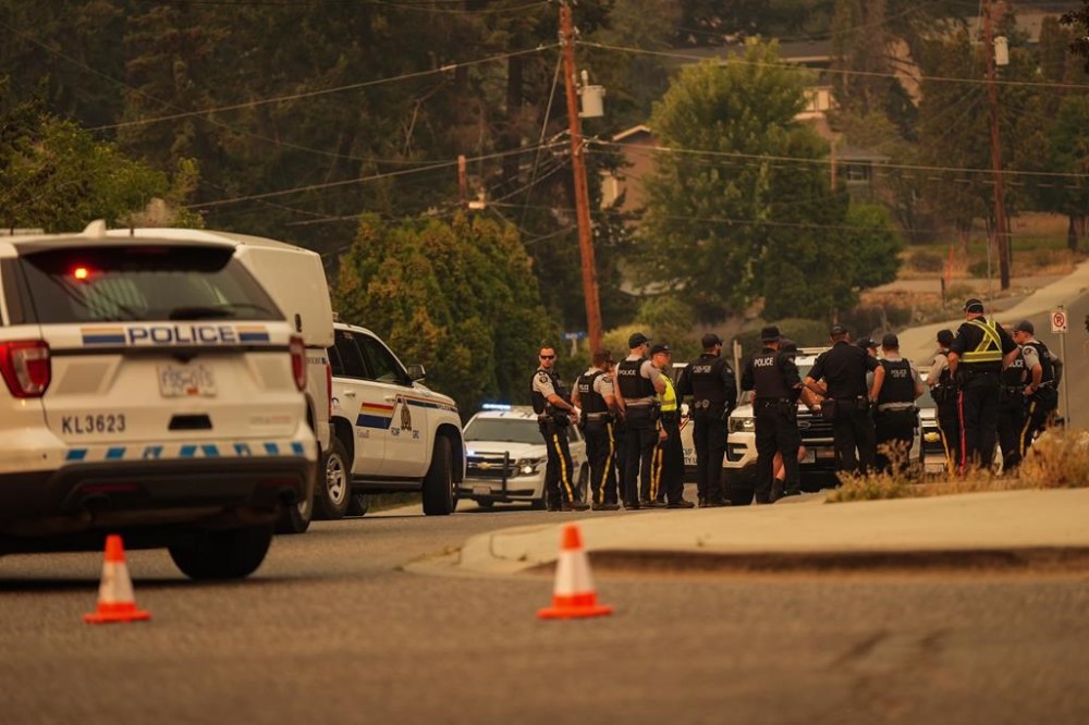RCMP officers meet at a roadblock after evacuating the Wilden neighbourhood near Knox Mountain due to a wildfire burning above homes, in Kelowna, B.C., Friday, Aug. 18, 2023. Premier David Eby says his government's decision to declare a British Columbia state of emergency allows the province to rapidly access tools and implement measures to support the rapidly evolving wildfire situation. THE CANADIAN PRESS/Darryl Dyck