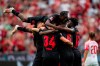 Leverkusen's Jeremie Frimpong jumps on goal scorer Jonathan Tah and other teammates after their side's second goal of the Bundesliga soccer match between Bayer Leverkusen and RB Leipzig, at the BayArena in Leverkusen, Germany, Saturday Aug. 19, 2023. (Marius Becker/dpa via AP)
