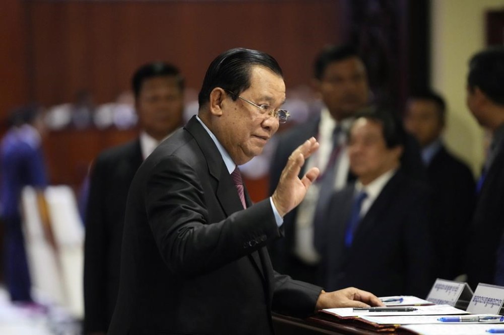 Cambodia Prime Minister Hun Sen, foreground, gestures as he signs in at a registration table before attending an assembly session in the National Assembly's hall in Phnom Penh, Cambodia, Tuesday, Aug. 22, 2023. (AP Photo/Heng Sinith)