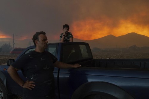 Local residents watch the wildfire in Avantas village, near Alexandroupolis town, in the northeastern Evros region, Greece, Monday, Aug. 21, 2023. Gale-force winds are fanning the flames of wildfires across Greece, including 53 new blazes that broke out early Monday amid hot, dry and windy weather that has sucked moisture from vegetation. (AP Photo/Achilleas Chiras)