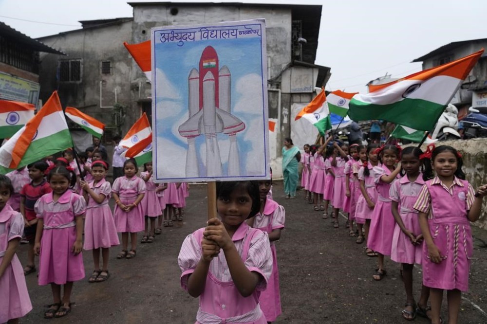 Children wave Indian flags at their school premises in Mumbai, India as they cheer for the successful landing of India’s moon craft Chandrayaan-3, on the moon surface, Tuesday, Aug.22, 2023. India’s previous attempt to land a robotic spacecraft near the moon’s little-explored south pole ended in failure in 2019. (AP Photo/ Rajanish Kakade)