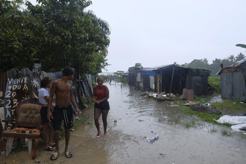 People walk between houses flooded by the rains of Tropical Storm Franklin, along the Ozama River in the Gualey neighborhood of Santo Domingo, Dominican Republic, Wednesday, Aug. 23, 2023. (AP Photo/Ricardo Hernandez)