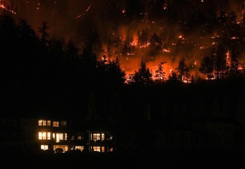 The McDougall Creek wildfire burns on the mountainside above a home in West Kelowna, B.C., on Friday, August 18, 2023. THE CANADIAN PRESS/Darryl Dyck