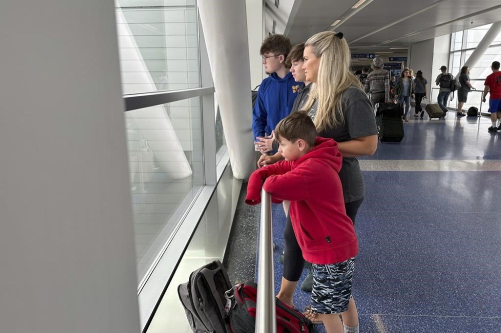 Mitzi Hale and her three sons look out a window at backed-up traffic due to the closure of Detroit Metropolitan Airport's McNamara Terminal on Thursday, Aug. 24, 2023, in Romulus, Mich. A flight originating from McNamara that was scheduled to take Hale and her boys to Florida for a vacation was delayed. Parts of Michigan received more than 5 inches of rain, which flooded tunnels leading to Detroit's main airport. (AP Photo/Mike Householder)