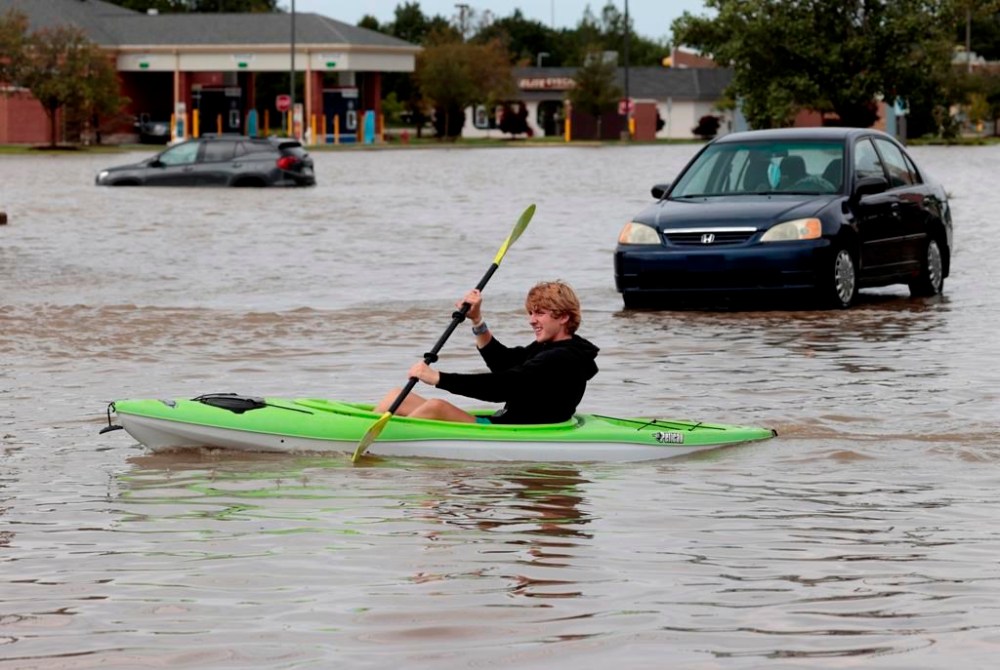 Aidan Ross, 17 of Canton, joins neighborhood friends in their kayaking going up and down Canton Center Road in Canton, Mich. looking to help stranded motorists in need of help after a big thunderstorm dumped several inches of rain in the area in the early morning hours of Thursday, Aug. 24, 2023. (Eric Seals/Detroit Free Press via AP)