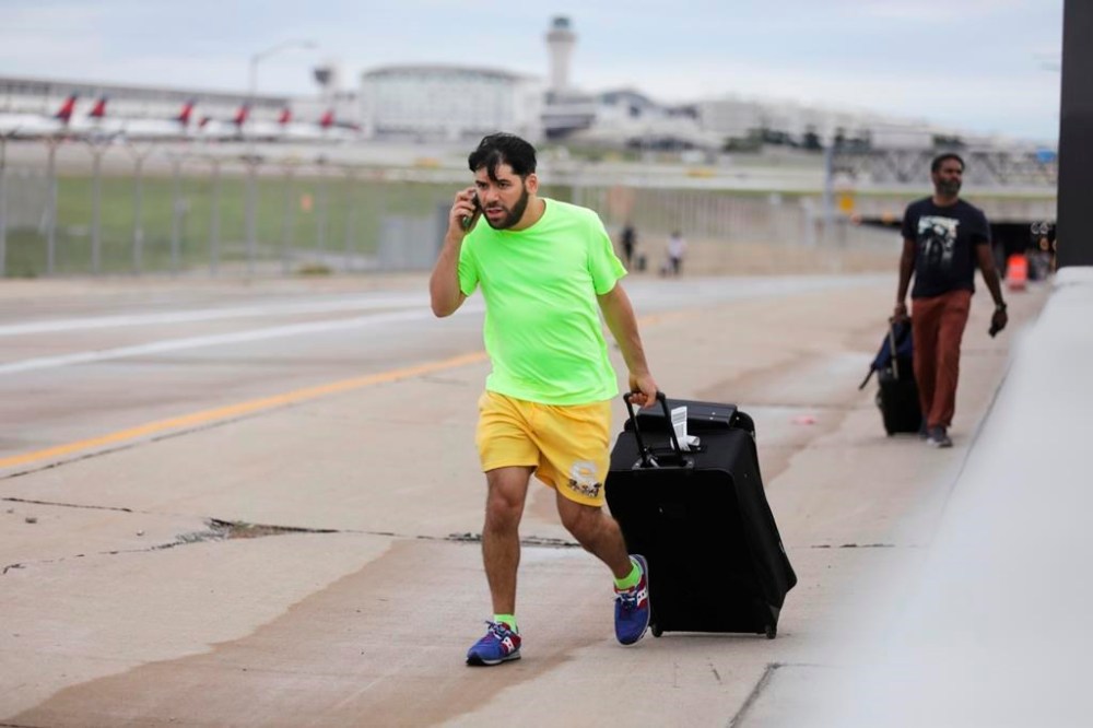 Jerald Joubran, 30, of Hollywood tries to find his family after his flight landed at McNamara Terminal and he trekked up the road at Detroit Metropolitan Airport where passengers and would-be travelers were stranded after overnight flooding in the area on Thursday, Aug. 24, 2023. (Kimberly P. Mitchell/Detroit Free Press via AP)/Detroit Free Press via AP)