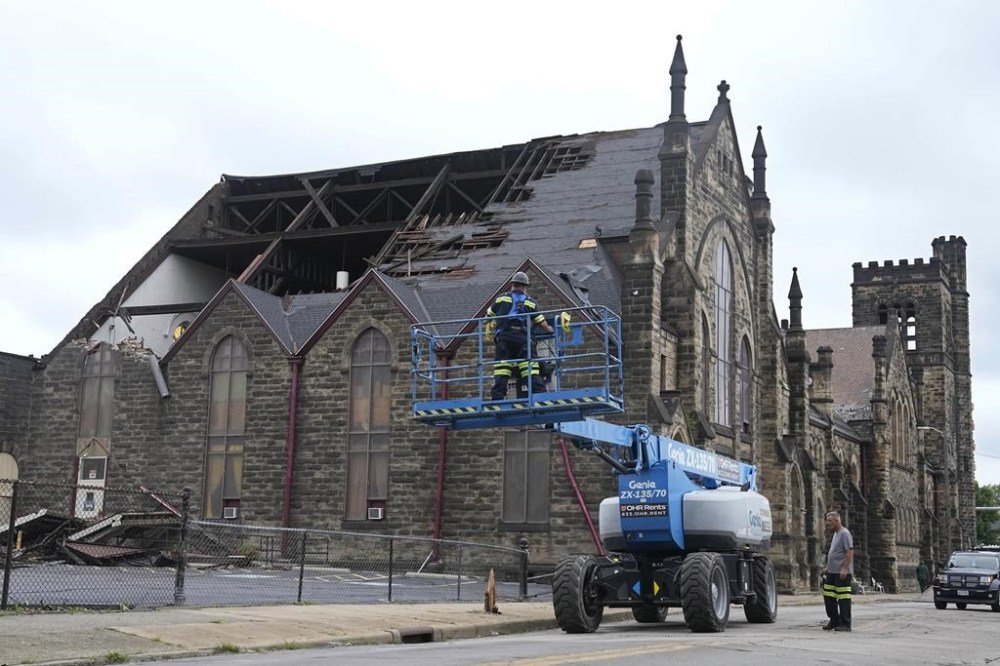 Equipment is moved into place outside the New Life at Calvary Church, Friday, Aug. 25, 2023, in Cleveland, after storms damaged 143-year-old church late Thursday, Aug. 24, 2023. (AP Photo/Sue Ogrocki)