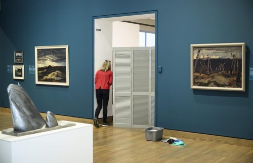 A staff member speaks to another past a partition used to block off the room where a climate activist threw paint on artist Tom Thomson's 