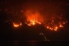 The McDougall Creek wildfire burns on the mountainside above a lakefront home, in West Kelowna, B.C., on Friday, Aug. 18, 2023. As students across British Columbia gear up for their return to school next week, parents in communities devastated by wildfires are grappling with what that may look like for their kids.THE CANADIAN PRESS/Darryl Dyck