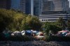 Tents and people are seen at a homeless encampment at Crab Park below the towers of the downtown skyline in Vancouver, on Sunday, Aug. 14, 2022. There is a stark contrast between public perception and the reality of how homeless people spend money, a University of British Columbia researcher says. THE CANADIAN PRESS/Darryl Dyck