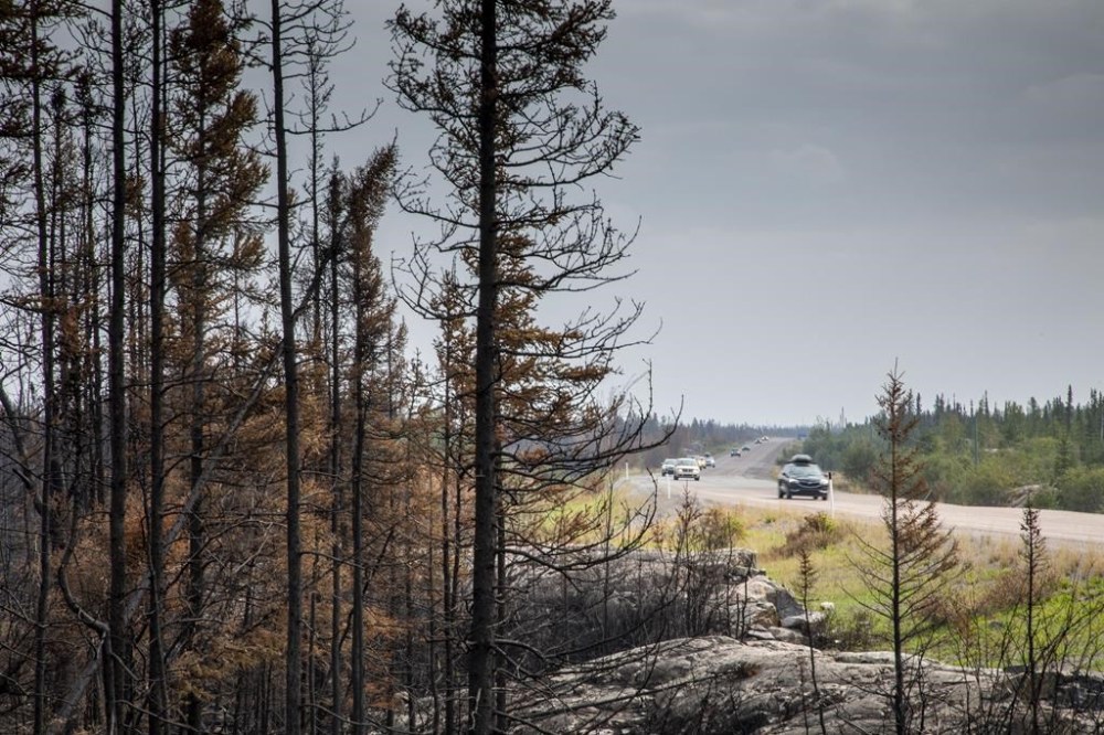 Fire activity along a key Northwest Territories highway is expected to kick up in the coming days, while Mounties say they'll stop a potentially large group from trying to re-enter when an evacuation order is still in effect. Evacuees from Yellowknife, territorial capital of the Northwest Territories, make their way along highway 3, at the edge of a burned forest, on their way into Ft. Providence, Thursday, Aug. 17, 2023. THE CANADIAN PRESS/Bill Braden