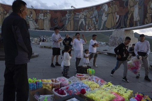 Visitors react as they throw darts at balloons to try and win soft toy prizes during a visit to the Zaisan Memorial, a monument that honors allied Mongolian and Soviet soldiers killed in World War II, in Ulaanbaatar, Mongolia on Wednesday, Aug. 30, 2023. (AP Photo/Ng Han Guan)