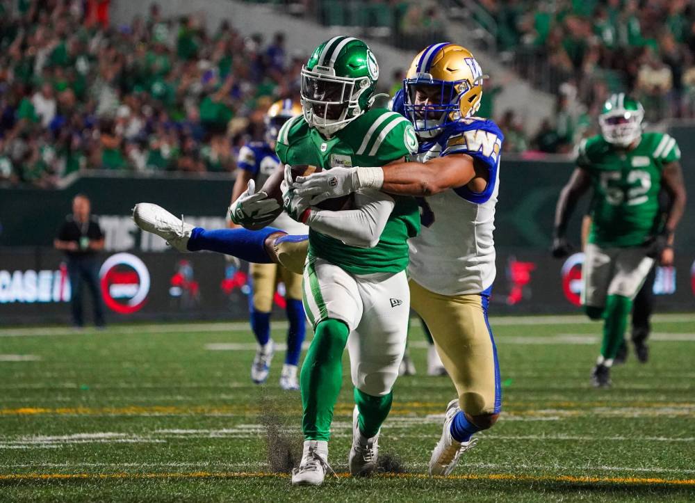 Saskatchewan Roughriders running back Jamal Morrow (25) is tackled by Winnipeg Blue Bombers linebacker Kyrie Wilson (19) during overtime of CFL Labour Day Classic football action in Regina, Sunday, Sept. 3, 2023. (Heywood Yu / The Canadian Press)