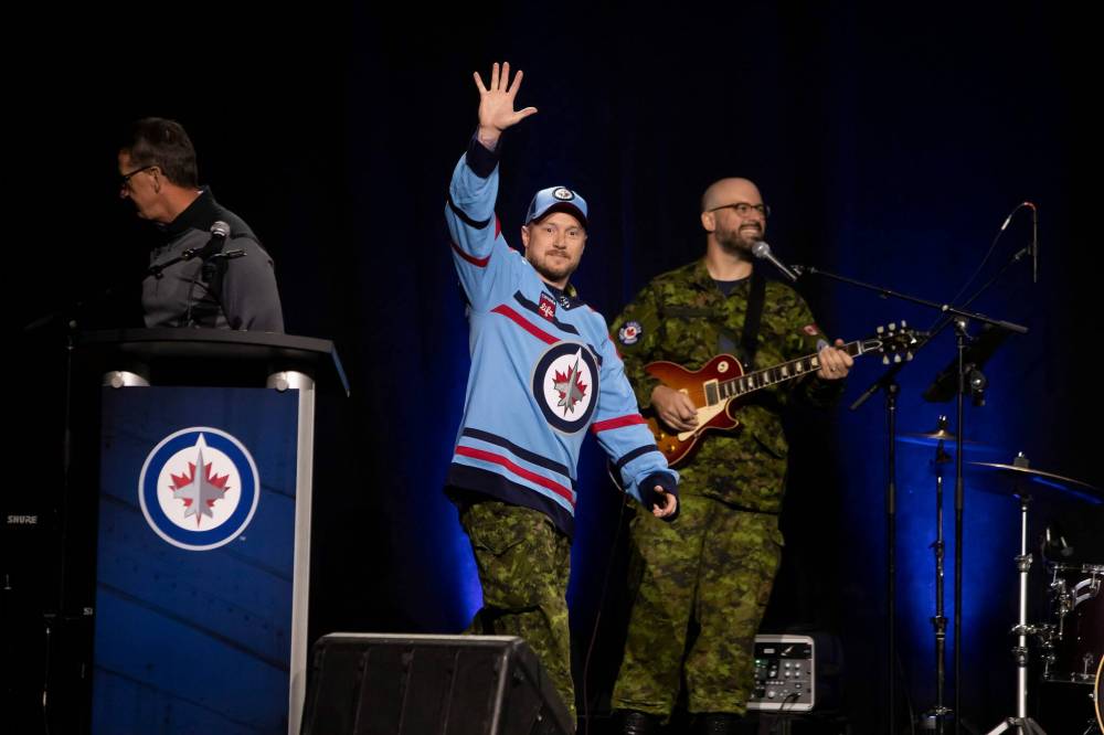 Royal Canadian Air Force Master Cpl. Kris Simundson waves to the crowd during the jersey unveiling Saturday. Joining Simundson on stage was Royal Canadian Air Force master warrant officer Anita Zacher and Maj.-Gen. Iain Huddleston, who is in command of 1 Canadian Air Division in Winnipeg. (Brook Jones/Winnipeg Free Press)