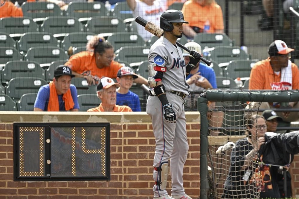FILE - Miami Marlins' Luis Arraez stand in the on-deck circle next to the pitch clock during the ninth inning of a baseball game against the Baltimore Orioles, July 16, 2023, in Baltimore. Major League Baseball is keeping the pitch clock the same for the postseason as it was for the regular season, brushing aside complaints from some players. (AP Photo/Terrance Williams, File)