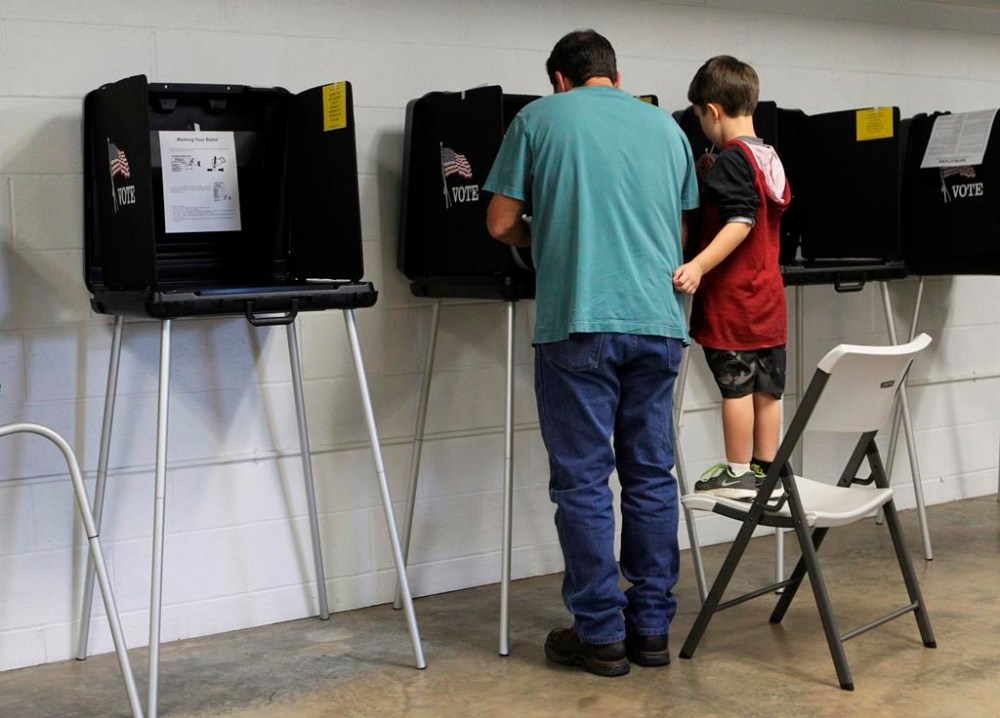 FILE -- Lanson Zaniroli, 4, watches his father Lance Zaniroli vote at First Christian Church on Nov. 4, 2014, in Shasta County, California. On Friday, Sept. 8, 2023, the California Legislature approved a bill that limits when local governments can count election ballots by hand. The bill was aimed at Shasta County, which had been preparing to hand count election ballots after local leaders voted to get rid of the voting machines they use to tabulate votes. (Andreas Fuhrmann/The Record Searchlight via AP, File)