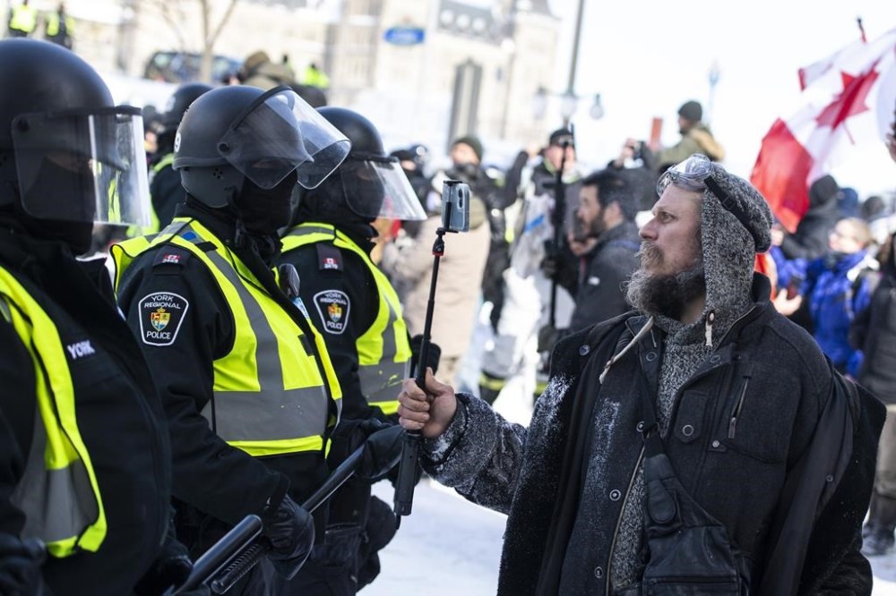 As thousands of demonstrators clogged the streets around Parliament Hill in early 2022, many of them did so with a phone in their hand. A protester records a police line with their phone as police move in to clear downtown Ottawa near Parliament Hill of protesters after weeks of demonstrations on Saturday, Feb. 19, 2022. THE CANADIAN PRESS/Justin Tang