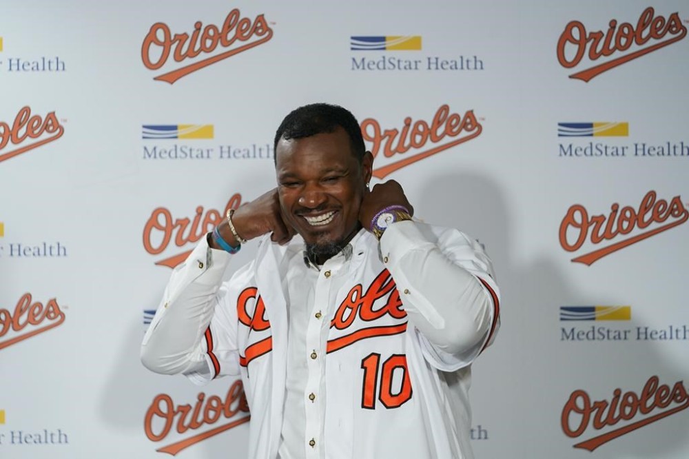 Former Baltimore Orioles player Adam Jones puts on a team jersey during a news conference in which he signed a contract to officially retire prior to a baseball game between the Orioles and the Tampa Bay Rays, Friday, Sept. 15, 2023, in Baltimore. (AP Photo/Julio Cortez)