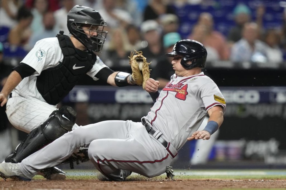 Atlanta Braves' Austin Riley, right, beats the throw to Miami Marlins catcher Jacob Stallings to score during the fifth inning of a baseball game Friday, Sept. 15, 2023, in Miami. (AP Photo/Lynne Sladky)