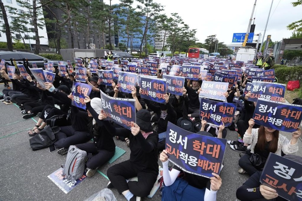Teachers hold up their banners during a rally to demand the better protection of their rights near the National Assembly in Seoul, South Korea, Saturday, Sept. 16, 2023. Following the suicide of an elementary school teacher in July, teachers across South Korea have been pushing for improved systems to protect teachers from widespread malicious complaints from parents. The signs read