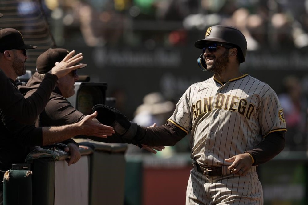 San Diego Padres' Trent Grisham, right, celebrates with teammates at the dugout after scoring against the Oakland Athletics on the throwing error by first baseman Ryan Noda during the fifth inning of a baseball game, Saturday, Sept. 16, 2023, in Oakland, Calif. (AP Photo/Godofredo A. Vásquez)